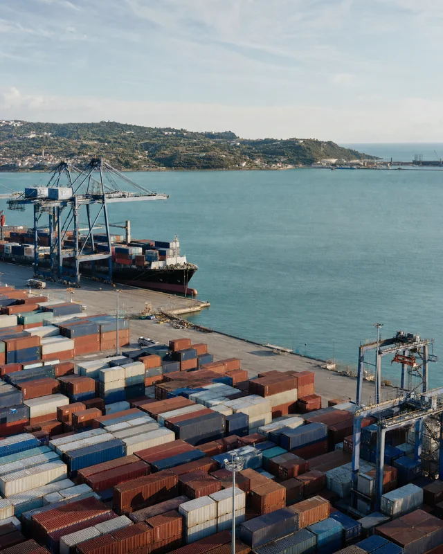 A coastal container terminal with cranes and a docked cargo ship.